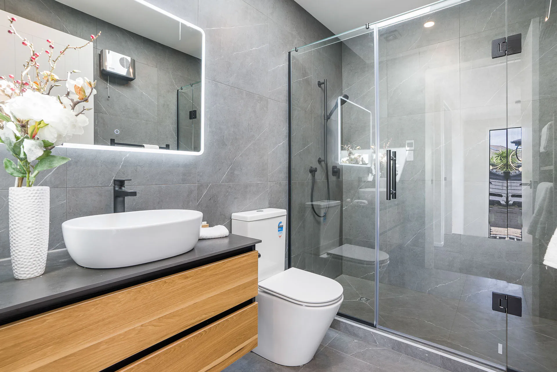 Bucklands Beach bathroom with a timber vanity, basin, toilet and a full glass shower enclosure.