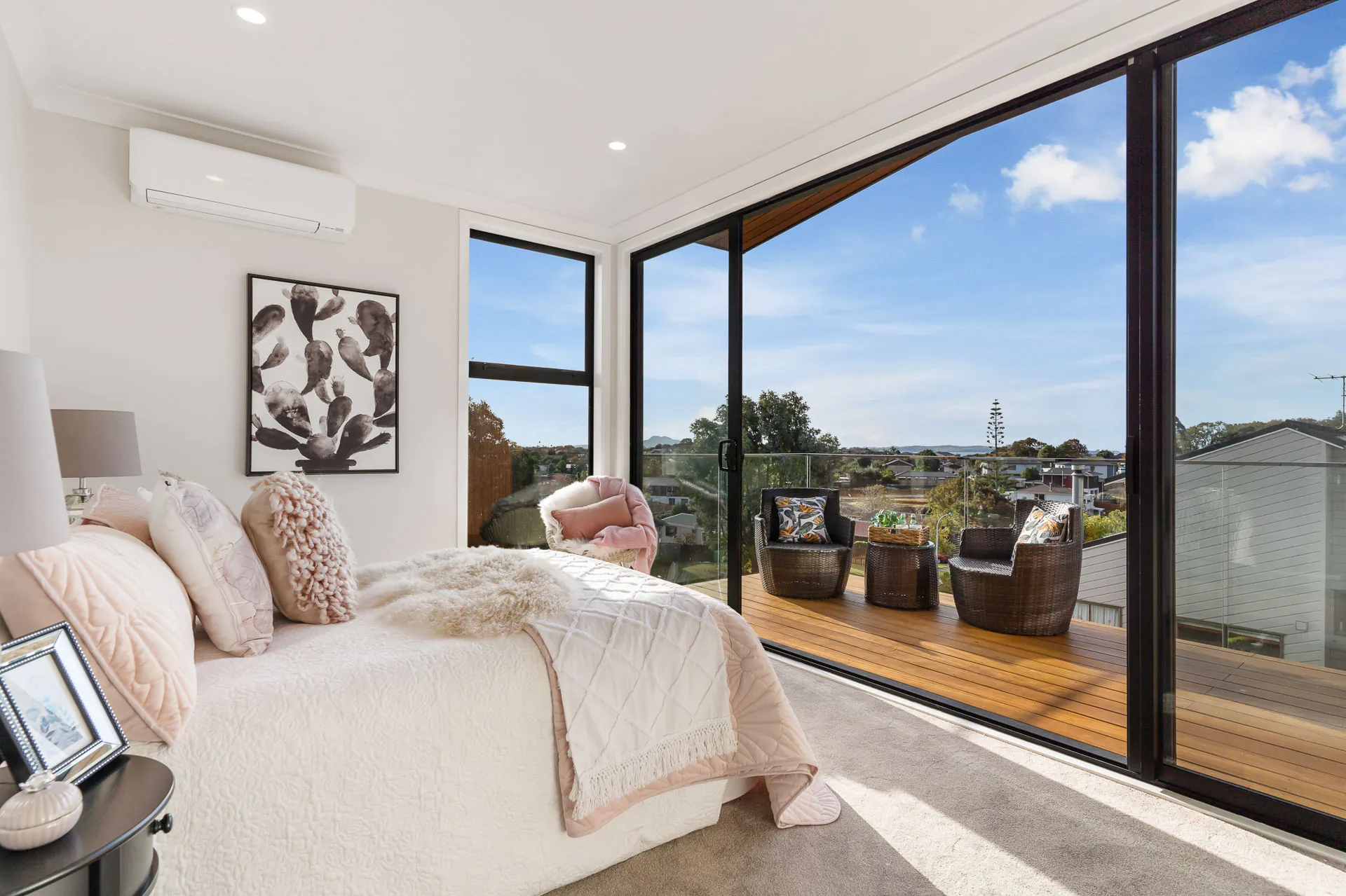 Bucklands Beach bedroom with full-height sliding glass doors opening onto a timber balcony.