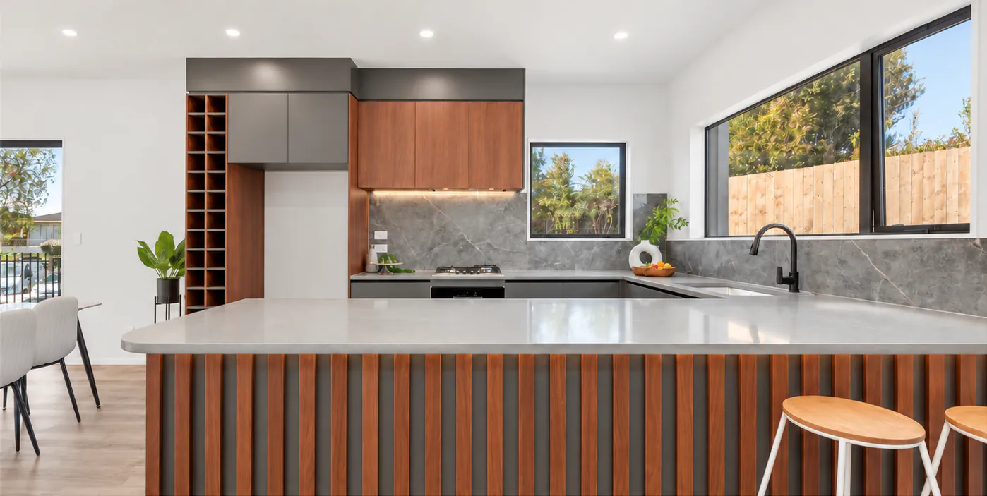 AI-retouched project photograph: the Botany Downs kitchen with timber cabinetry, grey benchtops and black tapware.