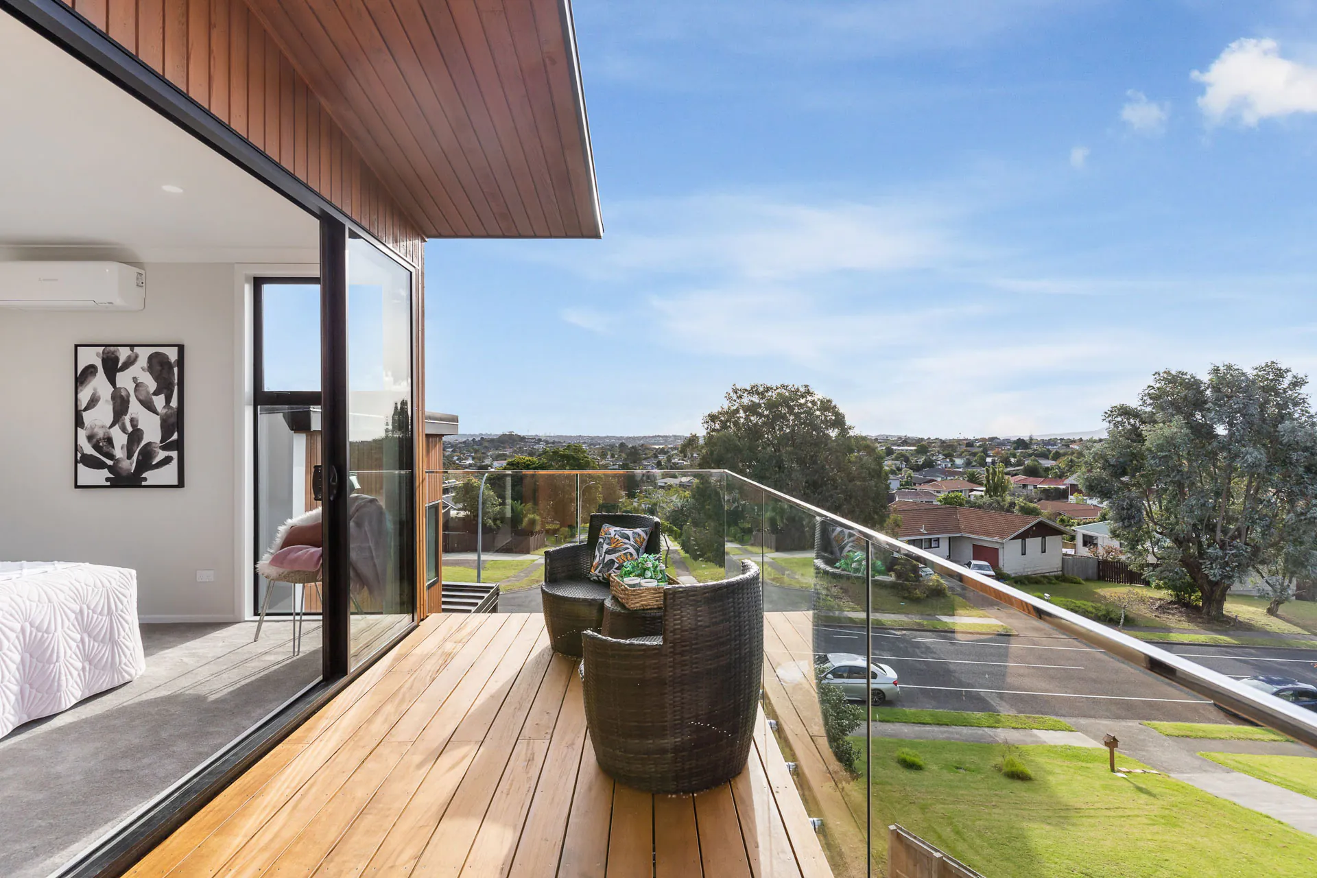 Bucklands Beach timber balcony with wicker seating, glass balustrades and views over the surrounding neighbourhood.